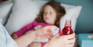 Woman holding cough syrup to give to daughter