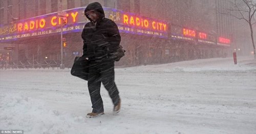 A пешеходна пресече улицата чрез издухване на сняг пред Radio City Music Hall в Ню Йорк на 23 Януари 2016