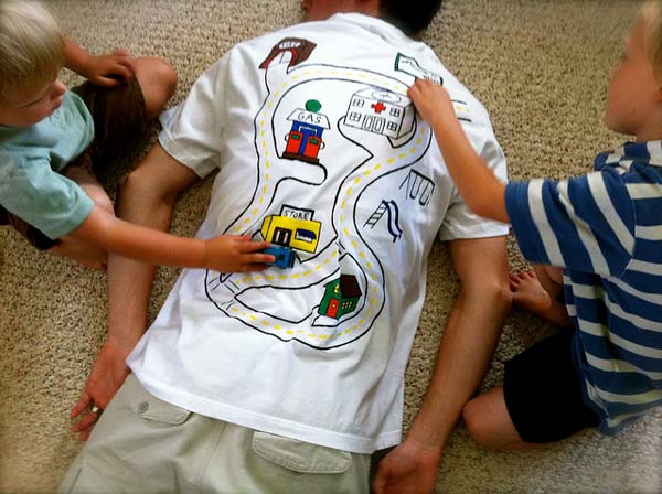 Нарисувайте писта на гърба на бялата тениска на татко, за занимавка на децата и масаж на бащата.