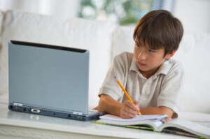 Mixed race boy doing homework and looking at laptop